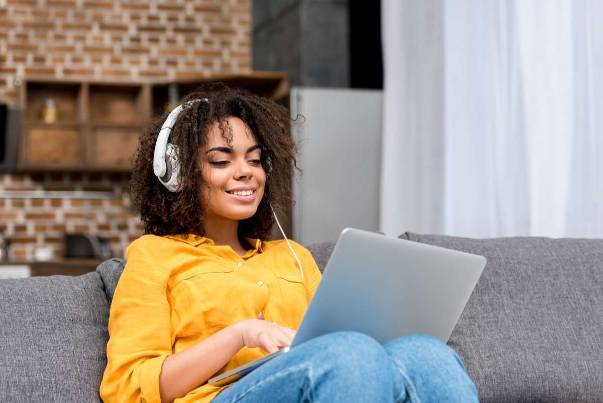 Happy young woman working with laptop and listening music at home (R) (S)