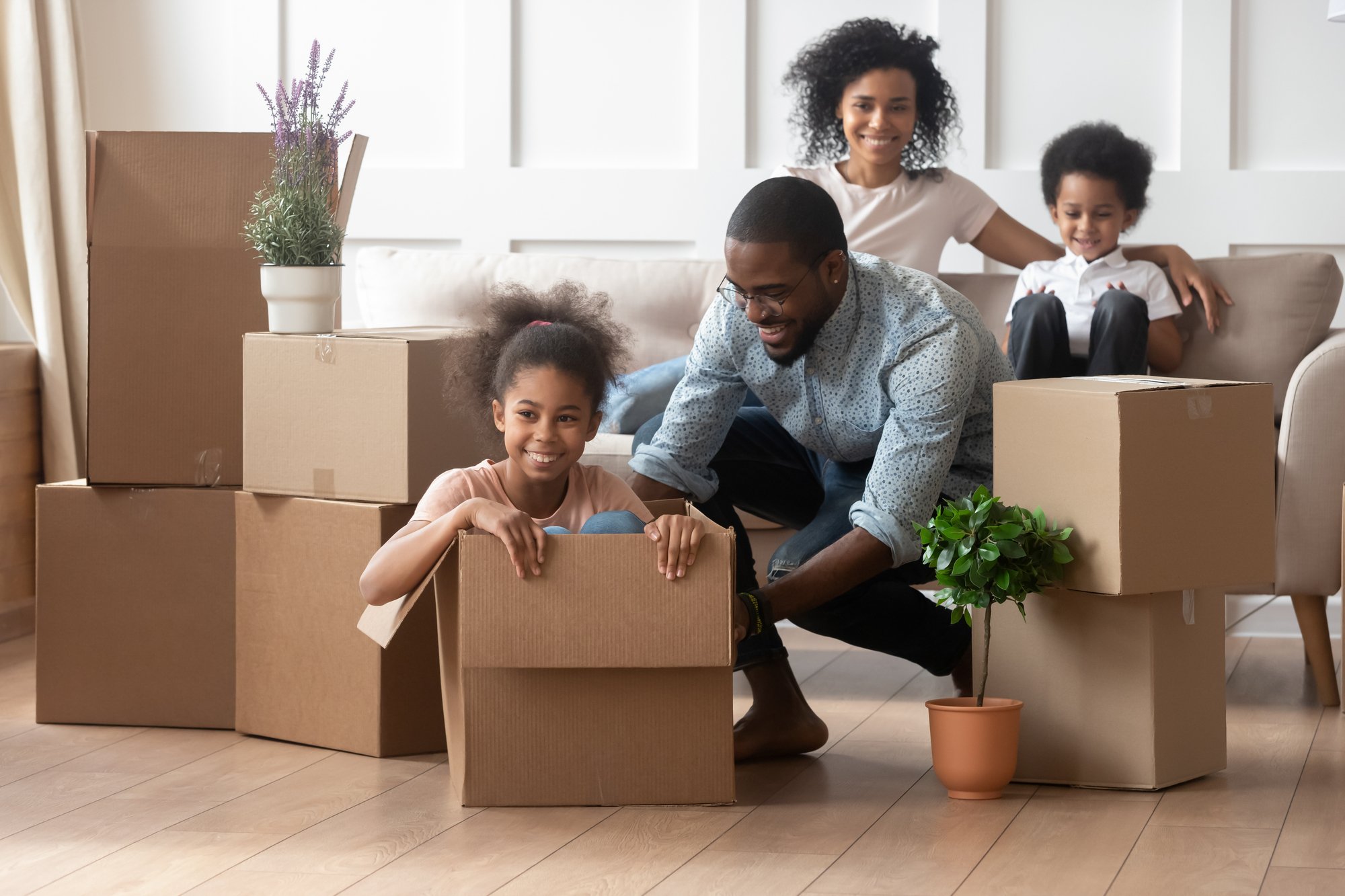 African father riding daughter sitting inside of big carton box