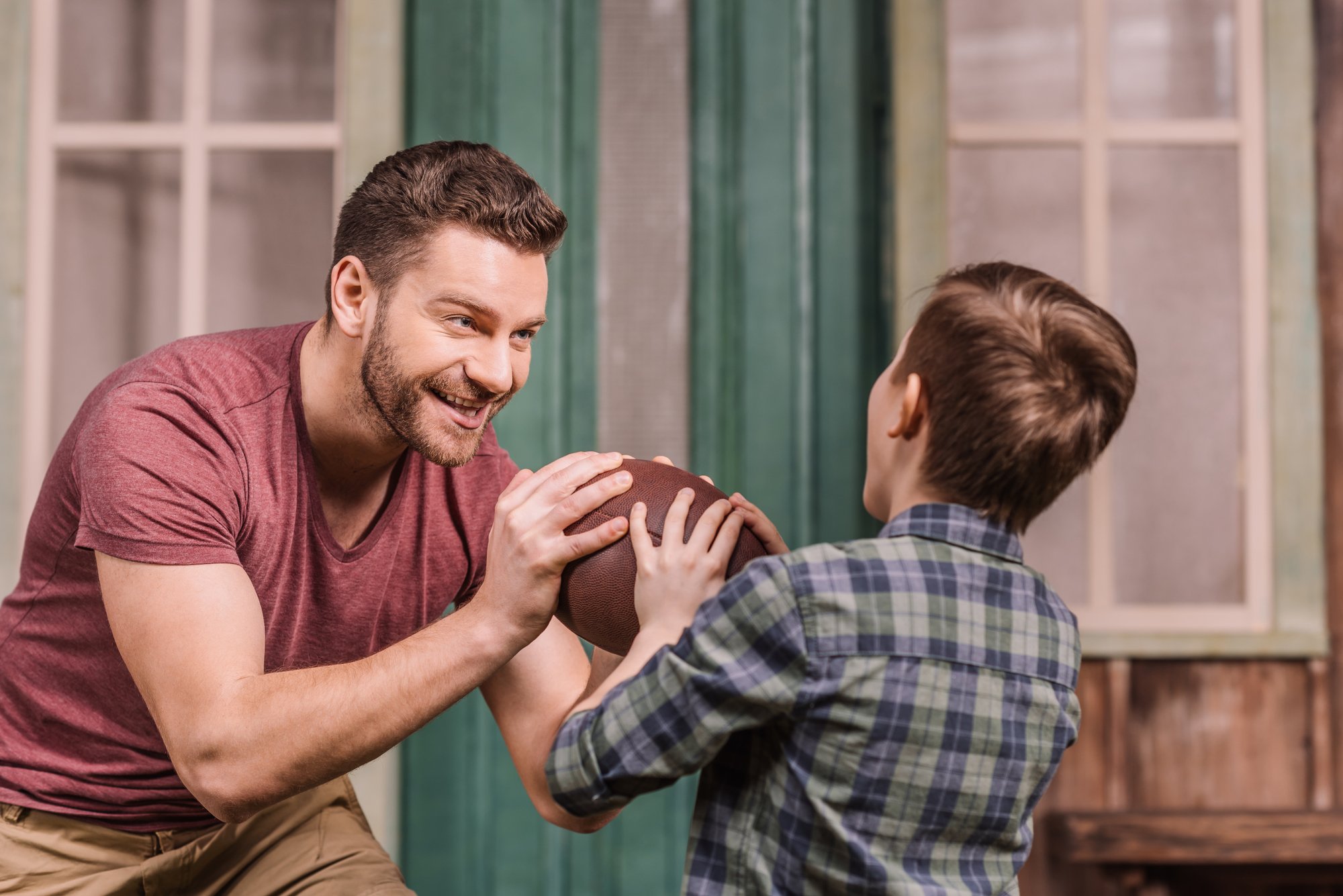 Father with son playing with ball at backyard