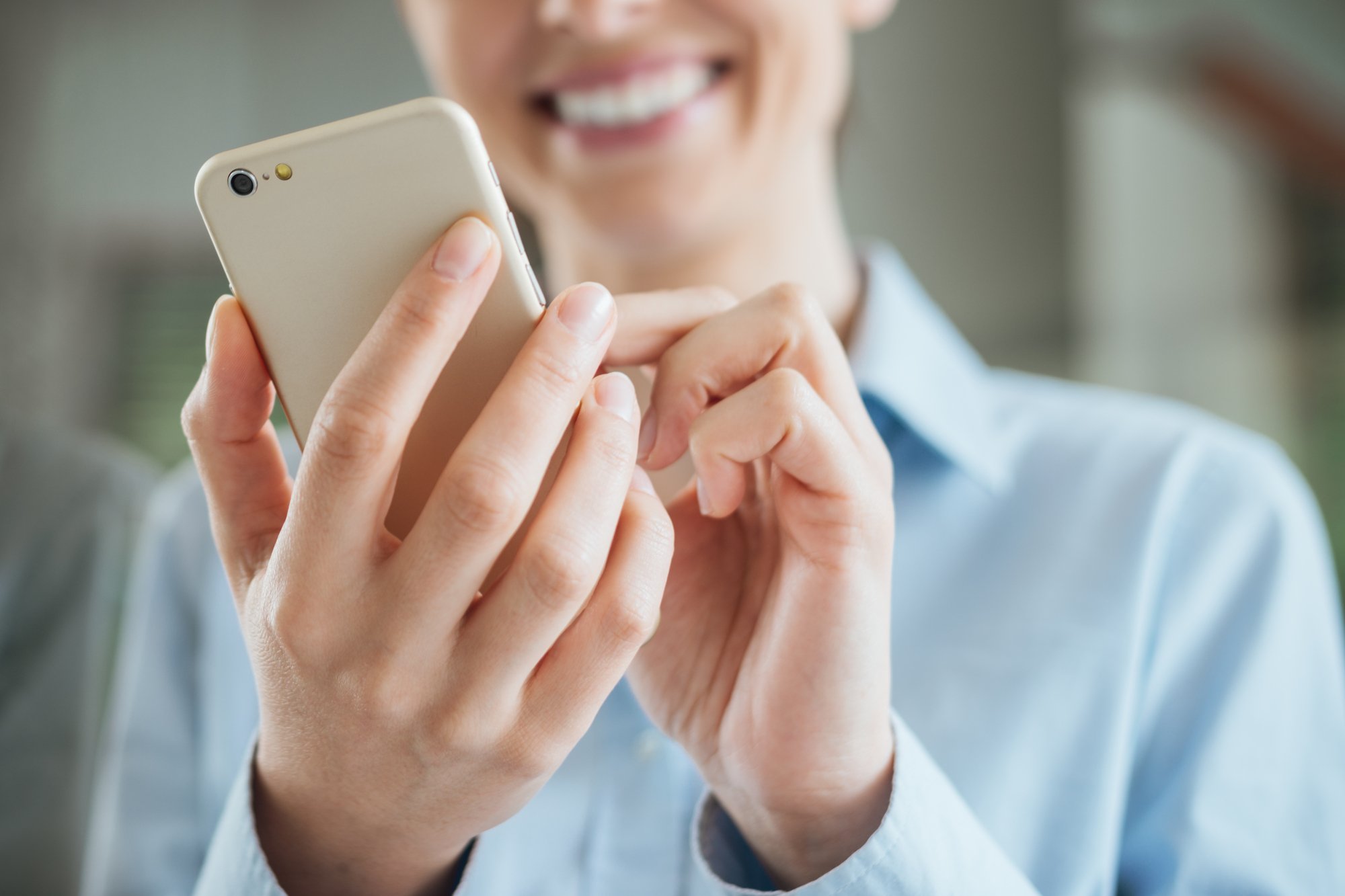 Woman using a smartphone and leaning on a window